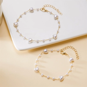 Close-up of golden anklet featuring white heart-shaped imitation pearls and lobster clasp