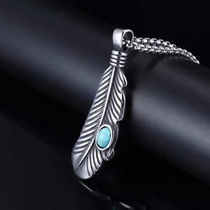 Macro view of punk style silver feather pendant featuring a round turquoise gemstone