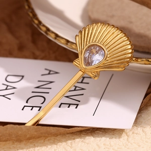Detail of a golden scallop shell hair clip inlaid with a sparkling teardrop zircon stone