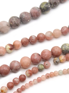 Macro detail of natural plum blossom jade round beads in pink green and brown tones