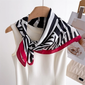 Detailed view of zebra print silk scarf with red border draped over a white top