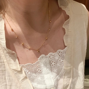 Elegante collana dorata con ciondoli a cuore e zirconi indossata da una modella