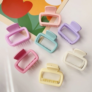 Flat lay of small square matte hair claws in vibrant macaron colors on a white surface