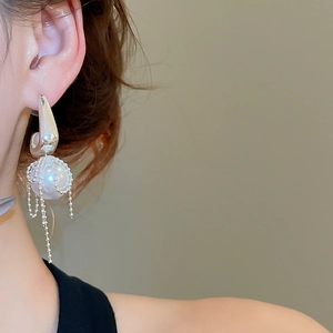 Close-up of pearl earrings with cascading silver fringe tassels on female model