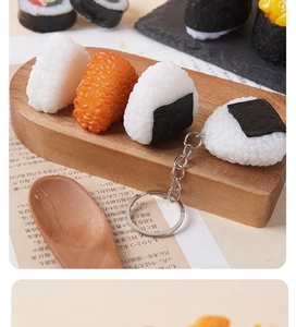 Close-up of realistic triangle sushi onigiri keychains on a rustic wooden tray
