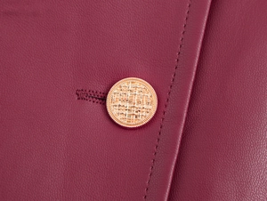 Macro-opname van een gouden getextureerde knoop en stiksels op een roze PU-leren jurk