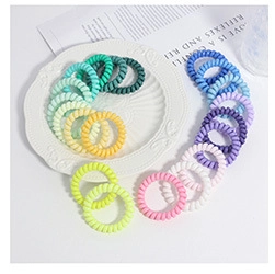 Dettaglio di elastici per capelli a spirale in vari colori pastello su un vassoio