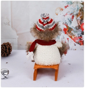 Detail of plush Christmas snowman with striped knit hat and red scarf on wooden sled