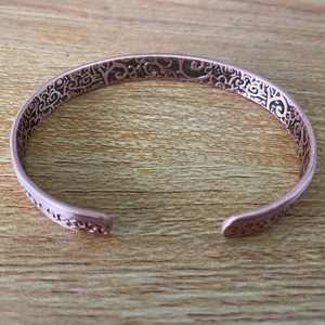 Detail view of adjustable red copper magnetic bracelet with intricate inner engravings