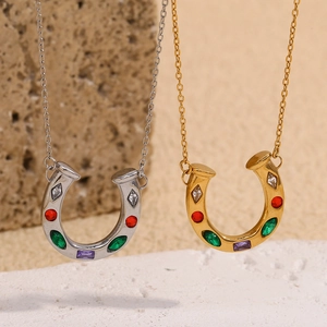 Horshoe necklace in gold and silver finish with colorful cubic zirconia on stone background