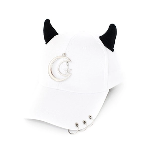 Close-up of white baseball cap with black demon horns and silver moon star charms