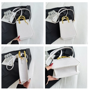 Macro detail of white crocodile embossed mini handbag with golden snake handle and strap