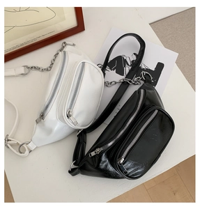 Detail of white and black faux leather belt bags with silver metal chains and zippers