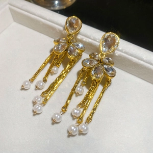Macro detail of golden flower tassel earrings with white pearls on a jewelry box