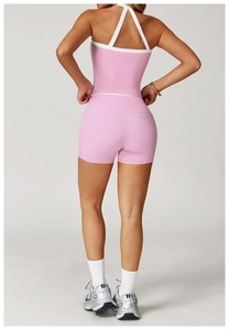 Detail van de roze rugloze yoga top met witte bandjes en sportshort met hoge taille