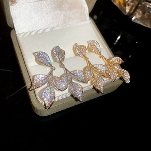 Detailed view of leaf tassel earrings with sparkling cubic zirconia in gold and silver