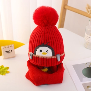 Detalle de gorro de punto rojo para bebé con diseño de pingüino y bufanda cálida a juego