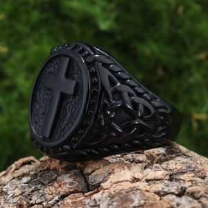 Macro shot of a vintage black cross pattern ring on a textured wood and moss background