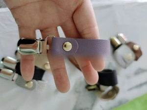 Nahaufnahme eines lila Leder-Hutclips mit Metallklammer und goldenem Druckknopf für Reisen