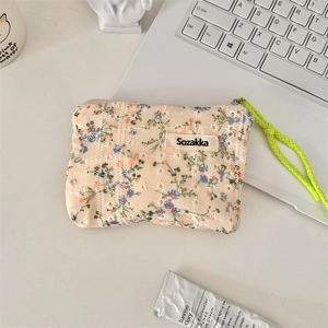 Floral embroidery small cotton pouch with zipper and green strap on minimalist desk