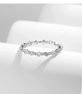 Detailed view of silver ring featuring alternating round and square cubic zirconia stones