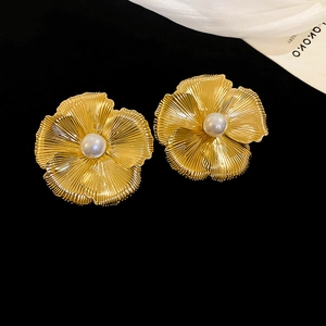 Detail view of gold flower earrings with brushed metal petals and center pearls