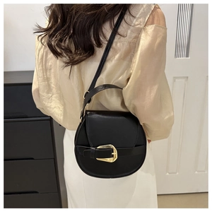 Details einer schwarzen Satteltasche aus Leder mit goldener Hufeisenschnalle und Gurt