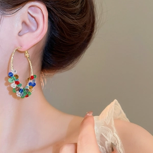 Close-up of colorful beaded hoop earrings on model featuring elegant metallic wrapping