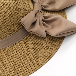 Dettaglio della trama in paglia e dell'elegante fiocco beige su un cappello estivo