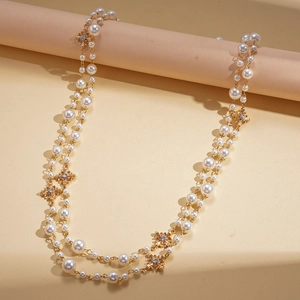 Collier de perles double rang avec fleurs dorées et strass sur fond beige élégant
