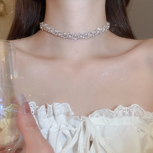 Close-up of elegant pearl and zircon necklace worn by a model with a shimmering collarbone