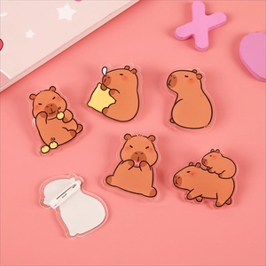 Cute acrylic capybara badges in various poses with pink background and safety pins