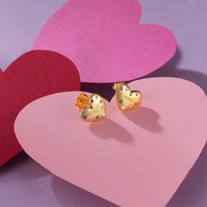 Macro shot of gold mama heart earrings with colorful zircon inlay on pink heart paper