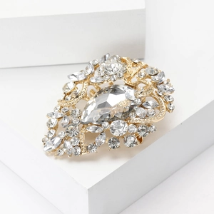 Close-up of elegant gold alloy brooch with sparkling rhinestones and pear-shaped stone