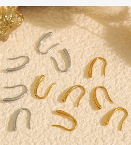 Boucles d'oreilles minimalistes en forme de U en or et argent sur surface texturée