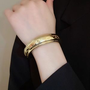 Gros plan sur un bracelet manchette doré avec une texture métallique martelée irrégulière
