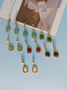 Flat lay of colorful oval gemstone pendant earrings with gold metal plating in various hues