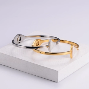 Polished stainless steel open bangle with triangular white shell inlay in gold and silver