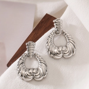 Detailed view of silver textured irregular geometric drop earrings on a rustic wood block