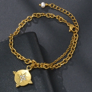 Detail of gold layered stainless steel bracelet with starburst pendant and white pearl