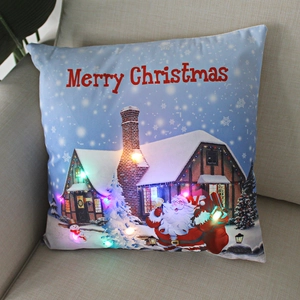 Close-up of LED Christmas pillow with glowing Santa pattern on a soft fabric sofa