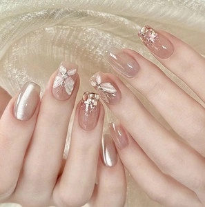 Detailed view of nude pink press-on nails with 3D butterfly, glitter, and cat-eye effects