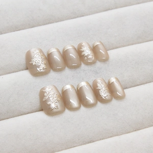 Handmade press-on nails with champagne pearl finish and 3D white floral embossing