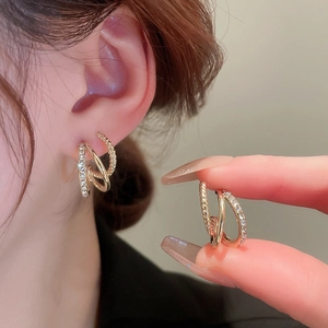 Detail of layered gold-plated hoop earrings with crystal pavé and twisted texture