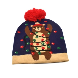 Close-up of navy blue knit Christmas hat with red pom-pom and beige cuff detail