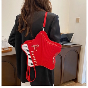 Detail of red pentagram star bag with piano keyboard pattern and gold bow charm