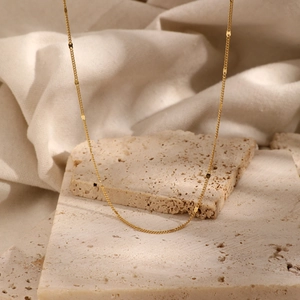 Minimalist 925 sterling silver gold chain necklace displayed on a textured stone base