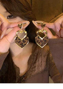 Gros plan de boucles d'oreilles cœur à motif léopard et cadre doré sur un modèle