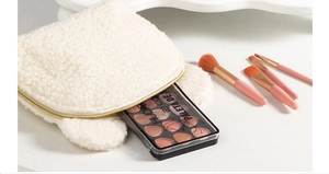 Close-up of white teddy plush bear makeup bag with zipper and cosmetic brushes