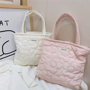 Detail of quilted floral handbag featuring plush texture and simple wish brand label